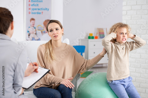 Naughty boy with adhd and sad mother during therapy with psychotherapist photo