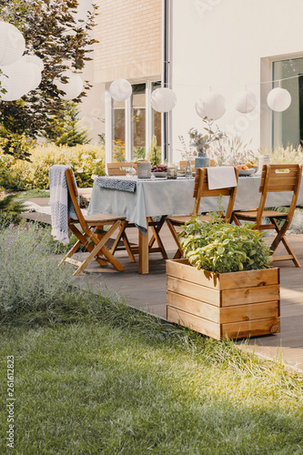 Real photo of a garden with a table, chairs, lamps and wooden box with plants