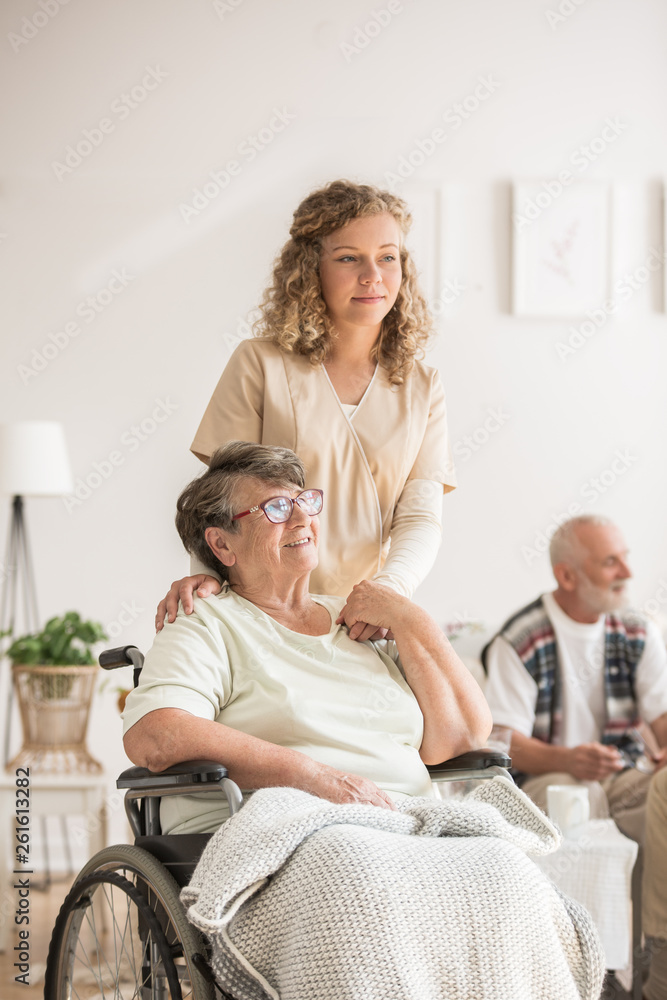 Nurse touching shoulders of her senior patient in a wheelchair Nurse touching shoulders of her senior patient in a wheelchair