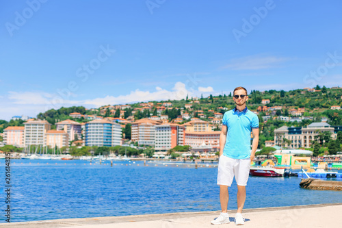 Young man in stylish clothes and sunglasses standing on pier on © Ivan