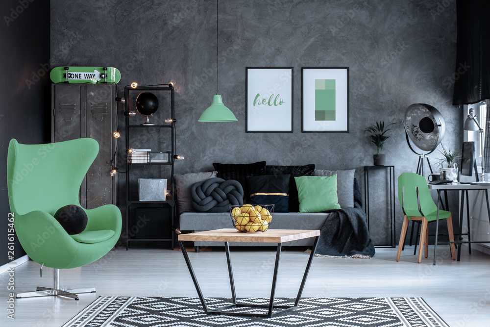 Φωτογραφία Green armchair next to wooden table in dark living room interior with posters above couch