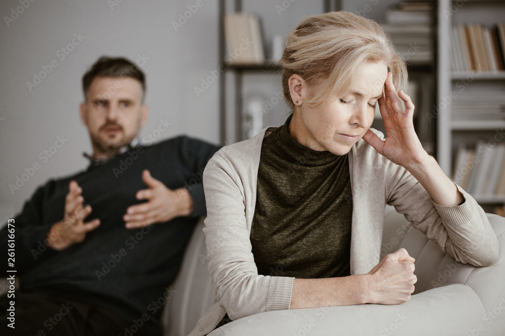 Φωτογραφία Depressed and tired wife with a headache in the middle of a conflict with a jeal