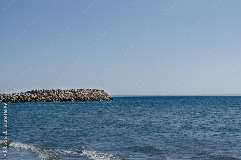Side view of stones  wave breaker  and  sea against  blue sky  during summer .