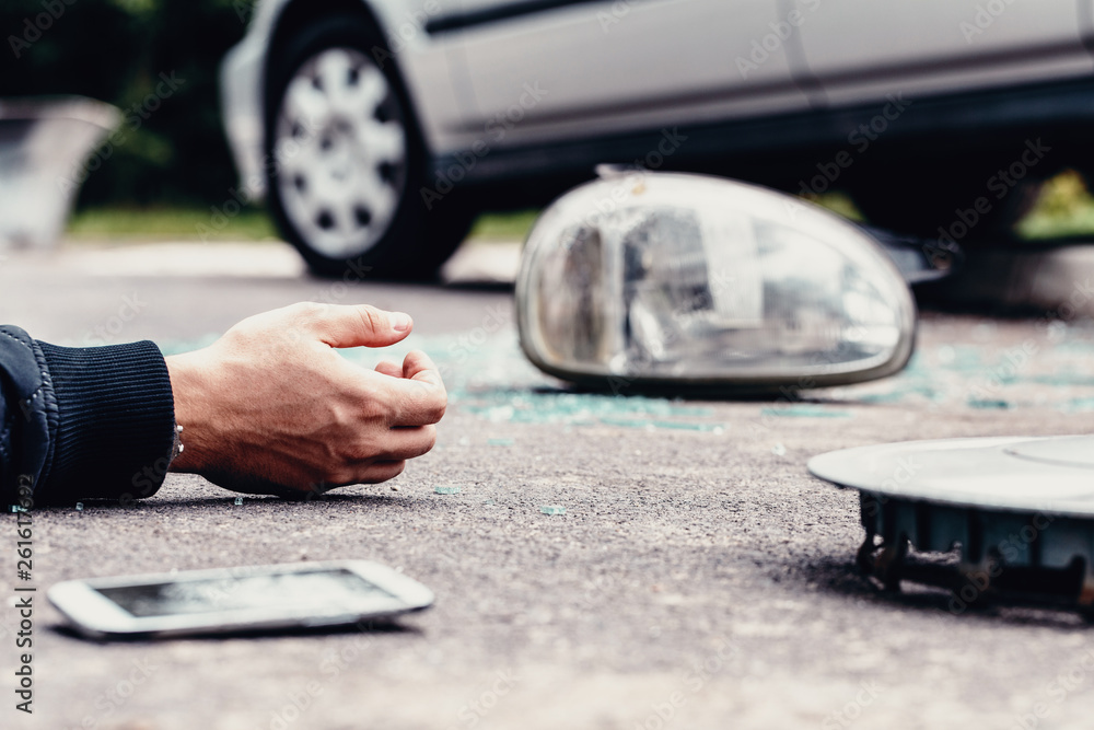 Φωτογραφία Human's hand on the ground next to broke car mirror and mobile phone after a cra