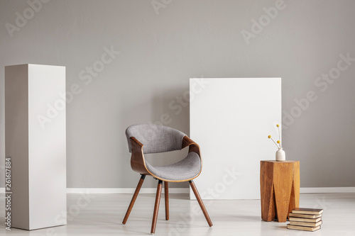 Stylish grey and wooden chair and coffee table between two white blocks of wood photo