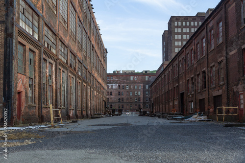 Street through a complex of derelict industrial buildings, daylight, horizontal aspect