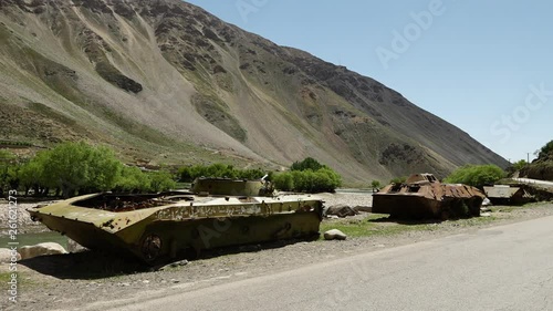 A steady, wide shot of neglected war tanks and solitude. photo