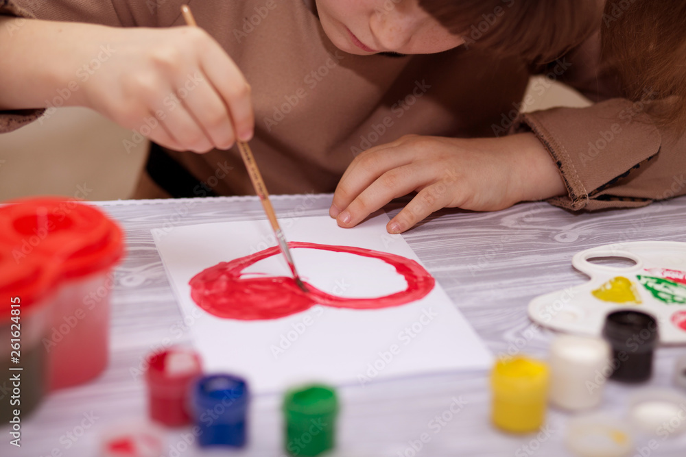 Child making homemade greeting card. Little girl paints heart on homemade greeting card as gift for Mother Day. Traditional play concept. Arts concept Child making homemade greeting card. Little girl paints heart on homemade greeting card as gift for Mother Day. Traditional play concept. Arts concept