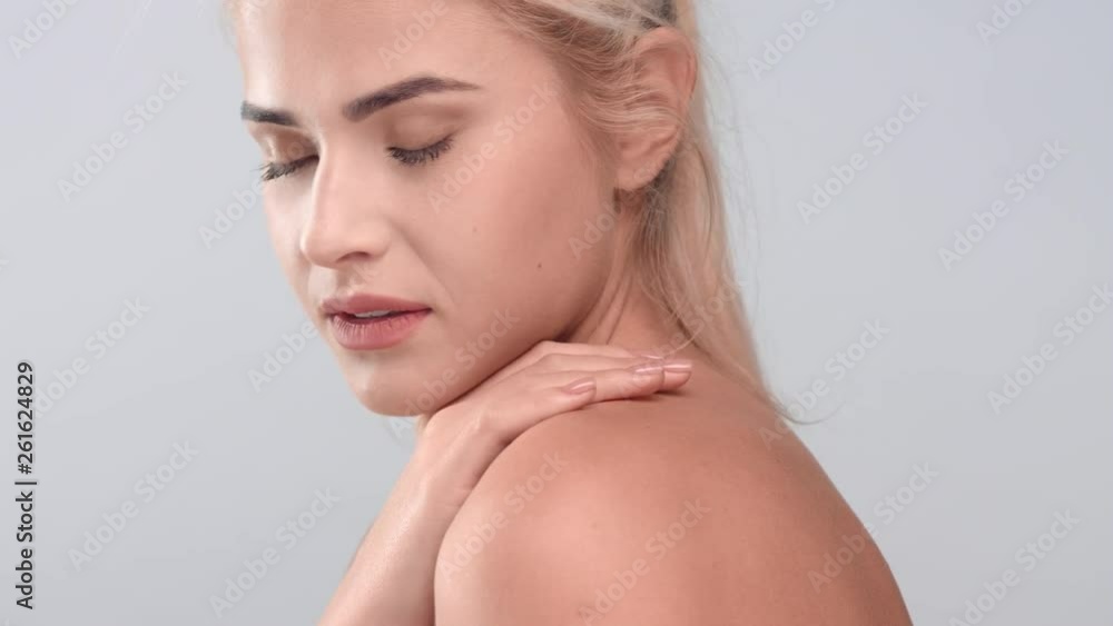 Woman gently touches her naked shoulders and looks at the camera Woman gently touches her naked shoulders and looks at the camera