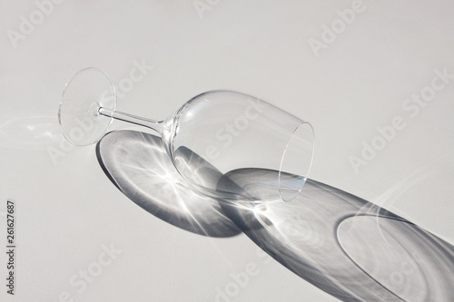 Wine glass lying on the table. Abstract shadows, sunlight.