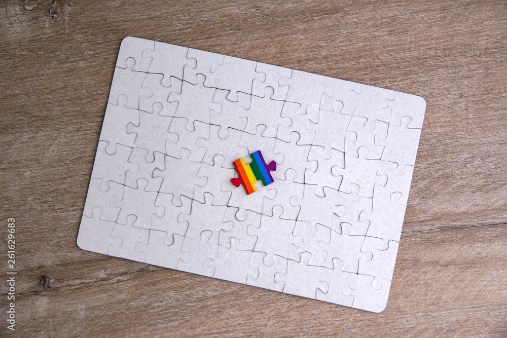 Place of LGBT people in the public structure: puzzle with the coloring of the rainbow flag against a white mosaic, top view Place of LGBT people in the public structure: puzzle with the coloring of the rainbow flag against a white mosaic, top view