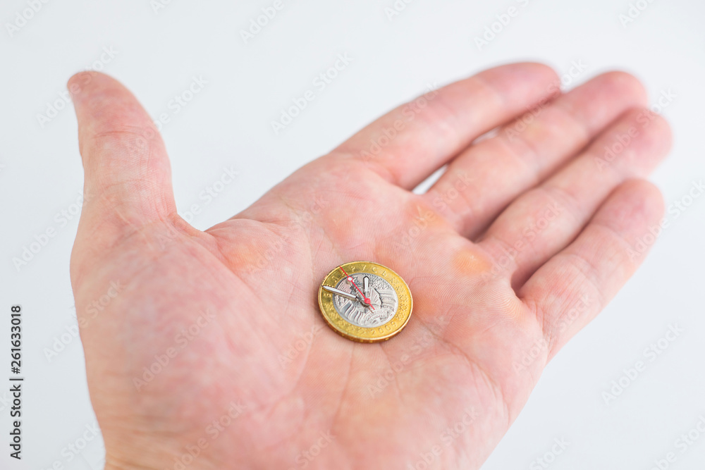 time and money, concept: second, hour and minute hands on a coin of 2 Belarusian rubles, on a person’s hand time and money, concept: second, hour and minute hands on a coin of 2 Belarusian rubles, on a person’s hand