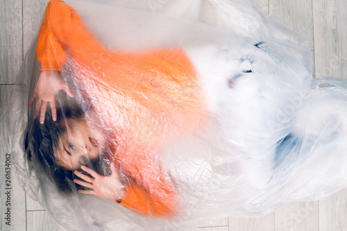 Fotografija Young woman wrapped in nylon transparent bag trapped frustrated freedom human tr