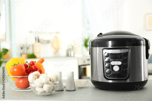 Modern multi cooker and products on table in kitchen