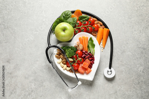 Flat lay composition with plate of products for heart-healthy diet on grey background photo