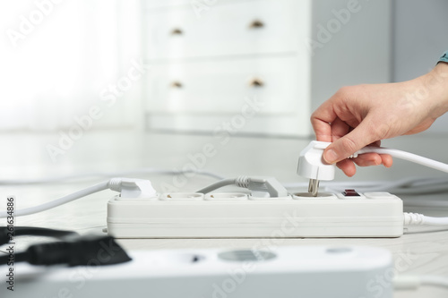 Woman inserting power plug into extension cord on floor indoors, closeup with space for text. Electrician's professional equipment photo