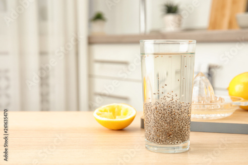 Composition with glass of water and chia seeds on table against blurred background, space for text