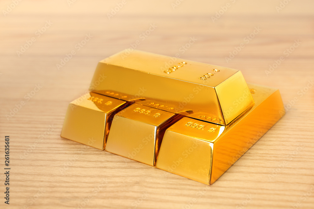 Stacked shiny gold bars on wooden table Stacked shiny gold bars on wooden table
