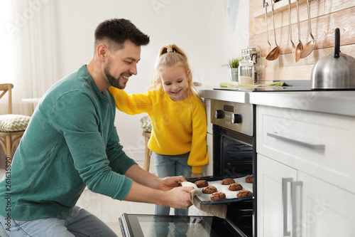 Father with his daughter baking cookies in oven at home