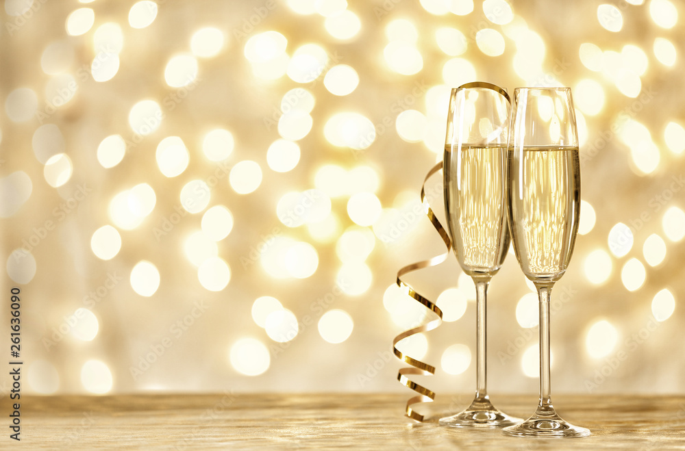 Glasses of champagne on table against blurred lights. Space for text Glasses of champagne on table against blurred lights. Space for text