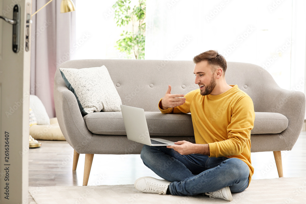 Young man using video chat on laptop in living room
