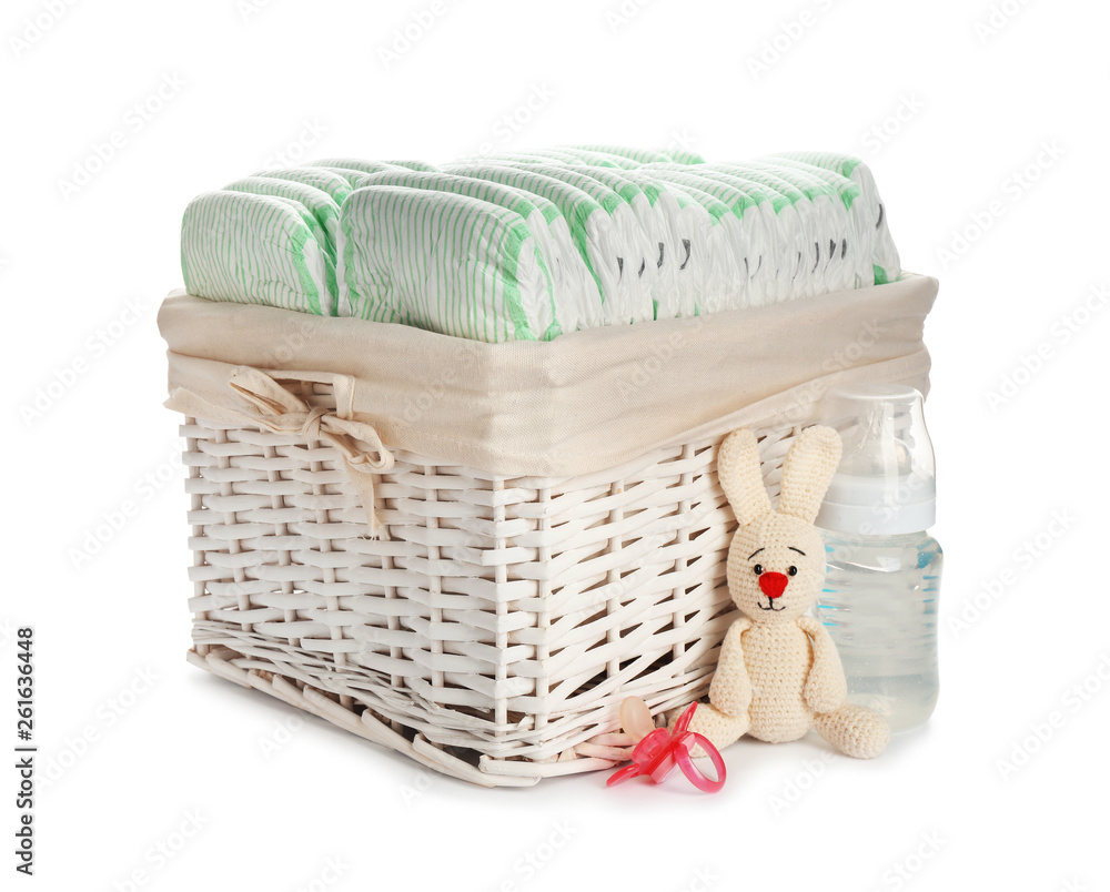 Obraz premium Wicker basket with disposable diapers and baby accessories on white background