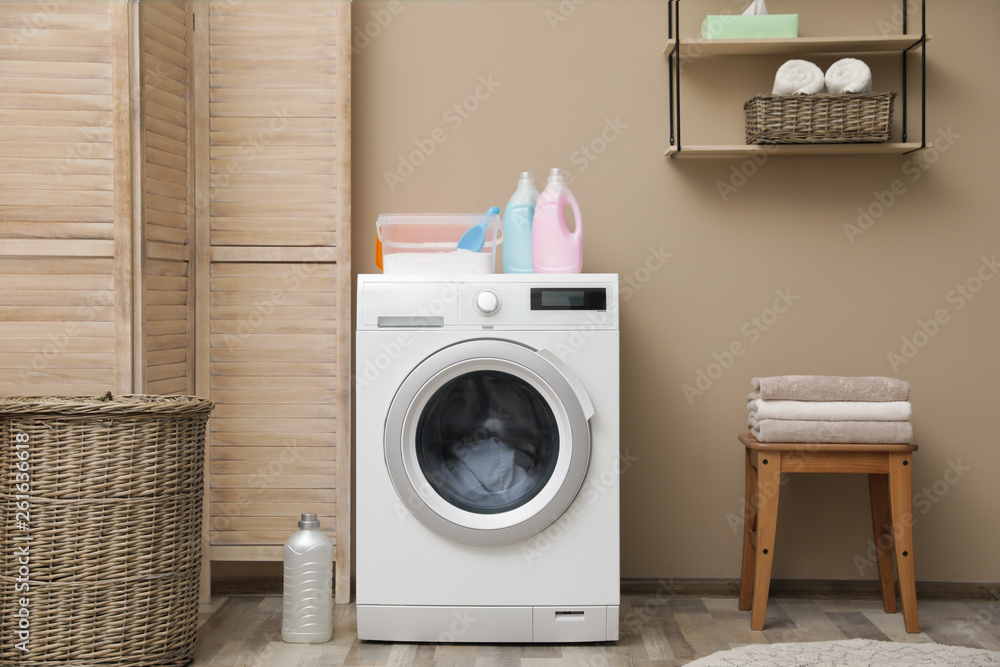 Modern washing machine near color wall in laundry room interior Modern washing machine near color wall in laundry room interior