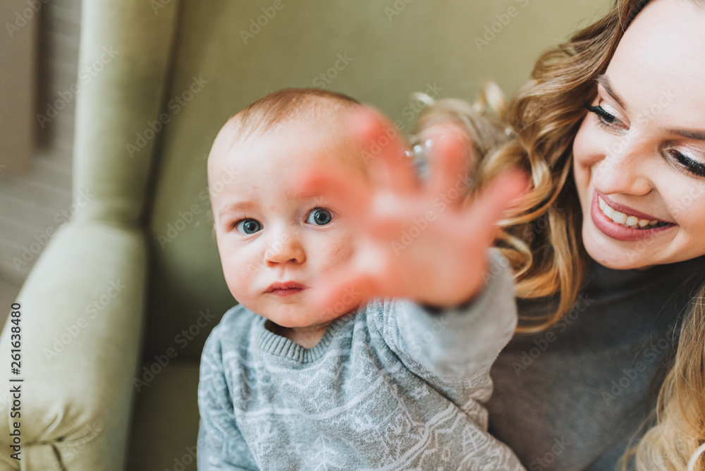 Beautiful young mother holding her cute son, he is reaching for the camera Beautiful young mother holding her cute son, he is reaching for the camera