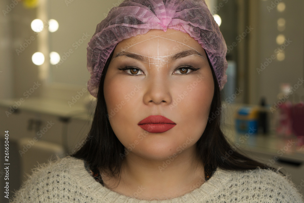 Microbleeding and eyebrow architecture. Portrait of girl with lines of symmetry on her face. Cosmetic procedure in spa salon. Microbleeding and eyebrow architecture. Portrait of girl with lines of symmetry on her face. Cosmetic procedure in spa salon.