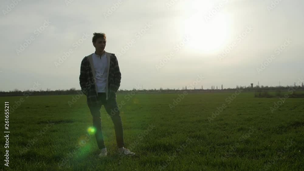 pensive boy standing in the green grass field at sunset pensive boy standing in the green grass field at sunset