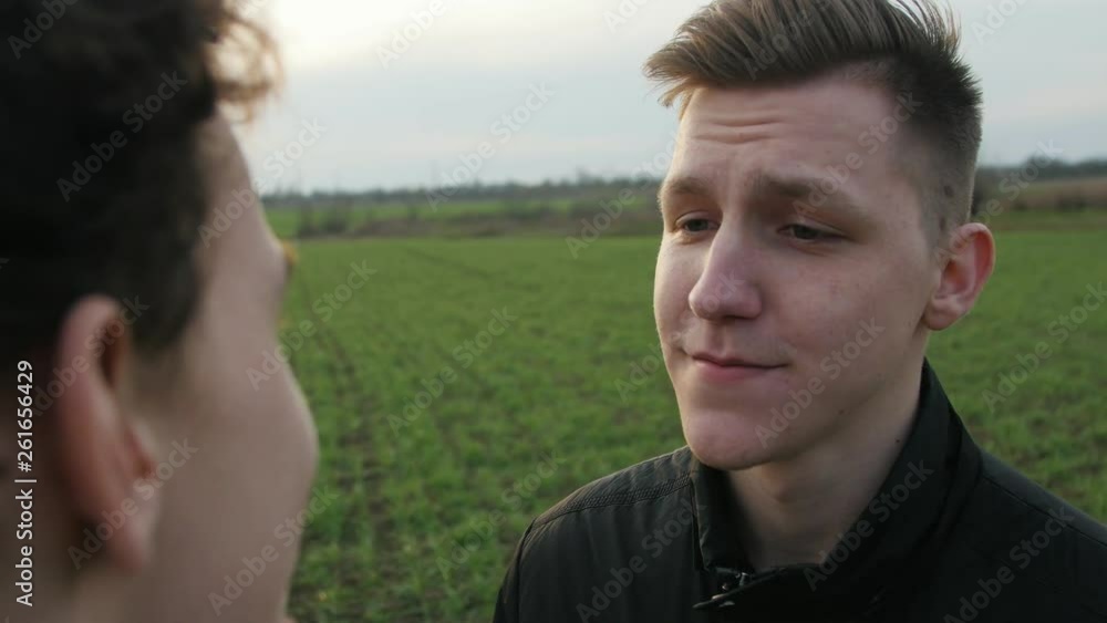 Cheerlful young friends talking in the nature background. Talking young people at sunset