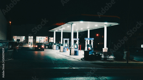 bright gas station on a very dark night in an urban city with few cars