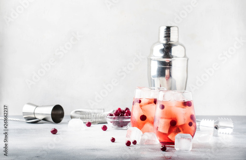 Cranberry cocktail cape kodder with ice, rosemary and berries, bar tools, gray bar counter background, top view