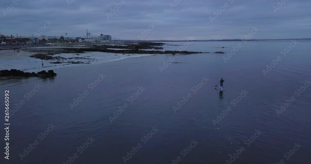Spiritual solo paddle boarder stroking slowly at beach Galway Promenade, Ireland west coast, drone shot Spiritual solo paddle boarder stroking slowly at beach Galway Promenade, Ireland west coast, drone shot