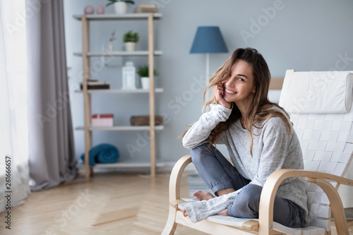 Beautiful happy woman looking at camera and smiling while sitting in a cozy chair. photo