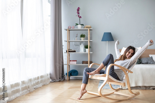 Happy woman resting comfortably sitting on modern chair in the living room at home.