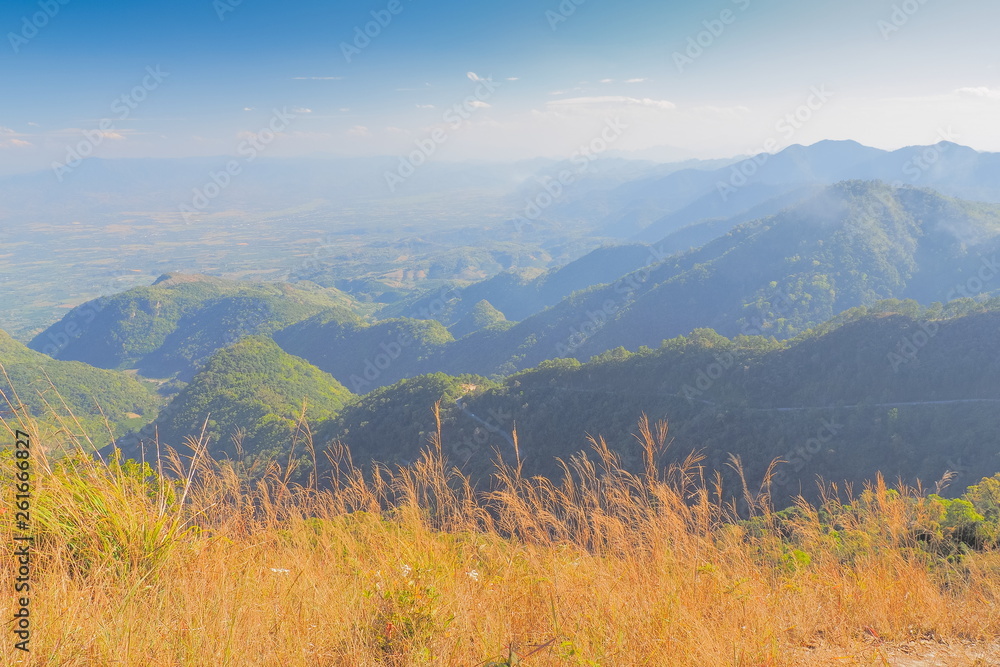 Mountain view morning on top of Doi Ang Khang above many hills and green forest cover with soft mist and blue sky background, Doi Angkhang, Chiang Mai, northern of Thailand.