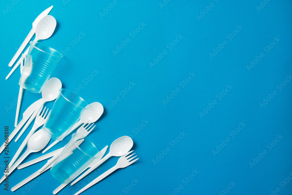 White singleuse plastic knives, spoons, forks on a blue background
