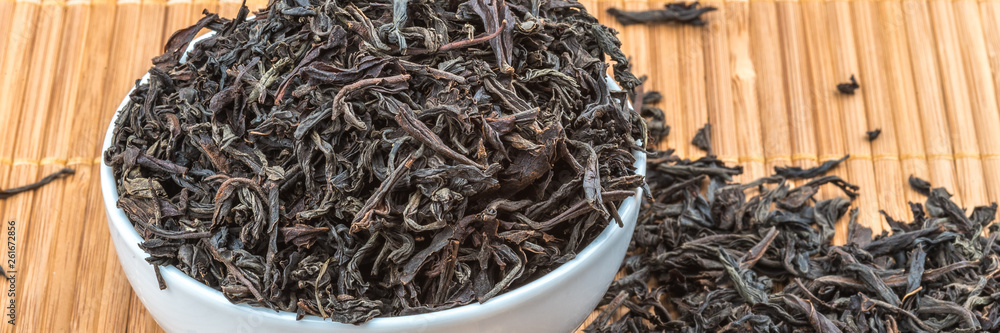 Dried tea is poured into a ceramic cup on a bamboo mat. Dried tea is poured into a ceramic cup on a bamboo mat.