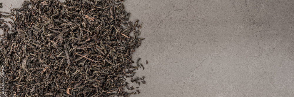 Dried tea is poured scattered on a grey textured background. Dried tea is poured scattered on a grey textured background.