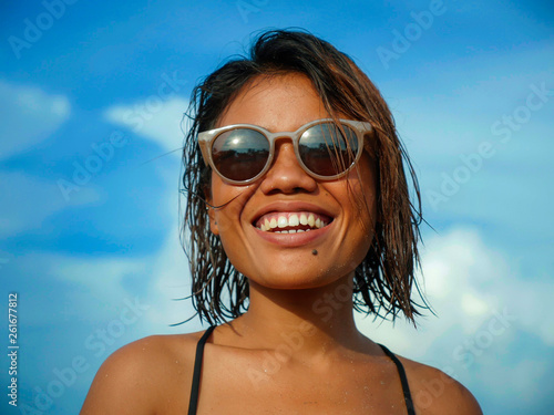 head and shoulders lifestyle portrait of young beautiful and sexy Asian girl in bikini and sunglasses enjoying holidays at tropical beach posing cool smiling happy at the sea