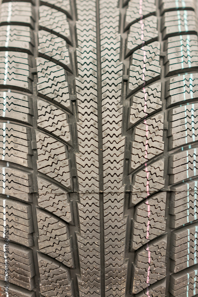 Close-up winter tire tread. Textured tire tread. Part of brand new modern winter car tire. vertical photo