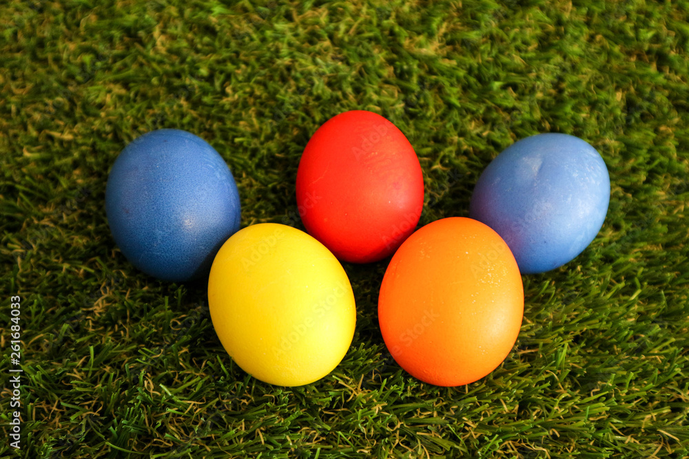 Five colorful bright easter eggs on green grass background