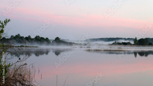 Morning dawn of the sun through the mist over the water. Early morning in the forest on the river.