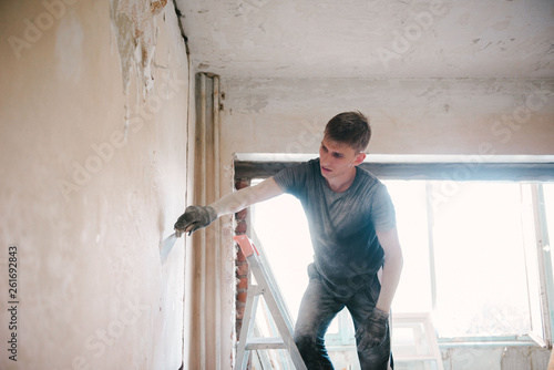Photos A man removes old paint from the ceiling with a spatula