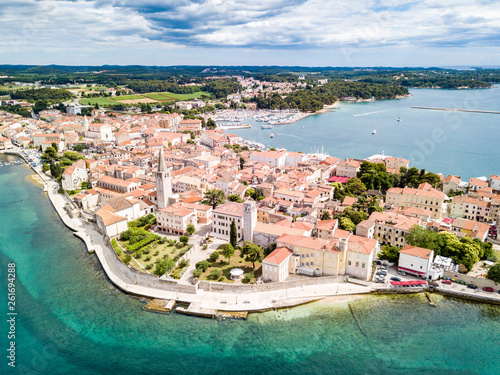 Croatian town of Porec, shore of blue azure turquoise Adriatic Sea, Istrian peninsula, Croatia. Bell tower, red tiled roofs of historical buildings, boat, piers. Euphrasian Basilica. Aerial view photo