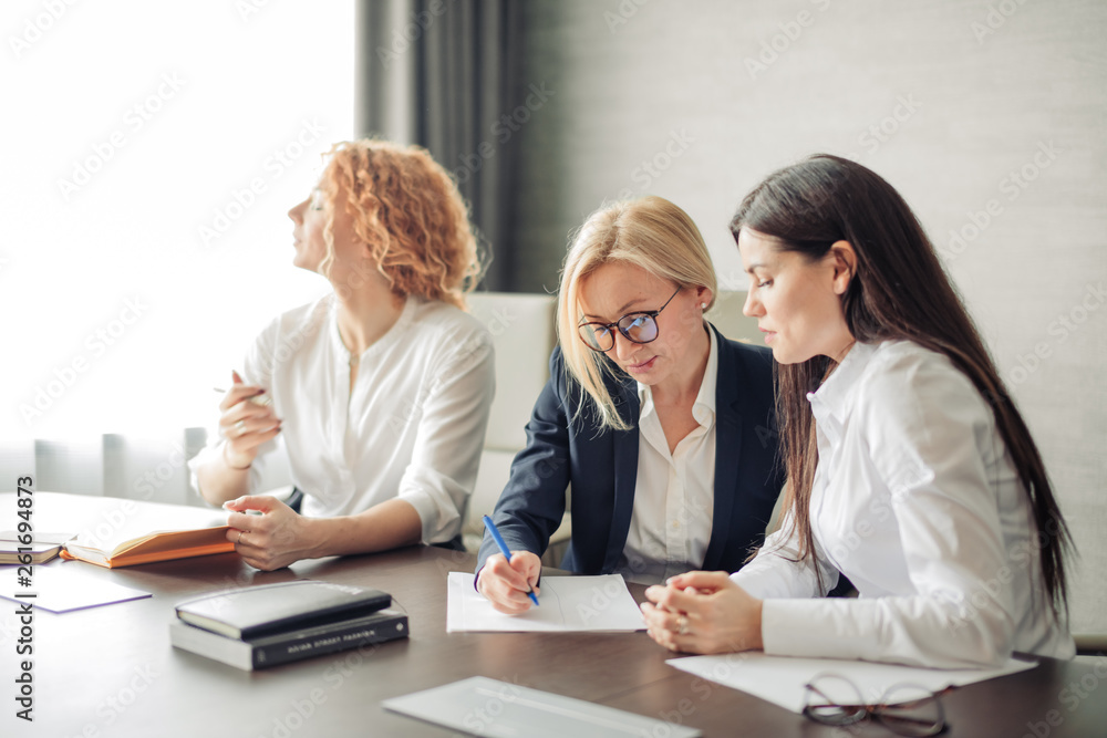 Three focused caucasian young business women with different hairstyle working together, brainstorming in office. Three focused caucasian young business women with different hairstyle working together, brainstorming in office.