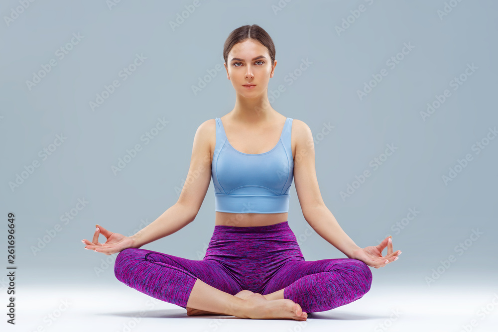 Young girl doing yoga, studio, gray background