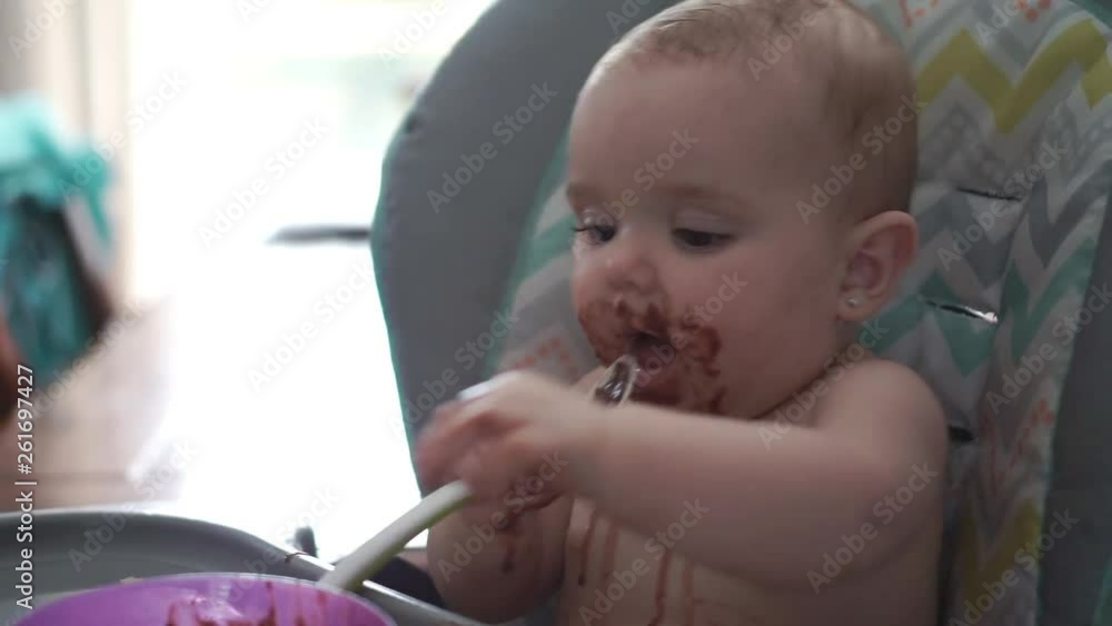 A Portrait Of Happy Young Baby girl In High Chair eat chocolate A Portrait Of Happy Young Baby girl In High Chair eat chocolate