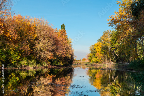 Autumn landscape trees with yellow leaves along the river and reflections in the water